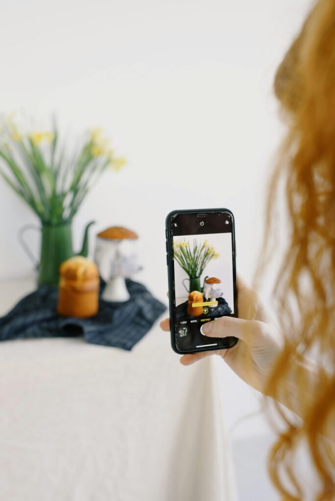 A person photographing a still life composition with a smartphone camera.